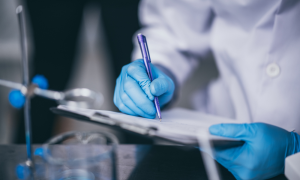 Lab Scientist recording data on a clipboard.