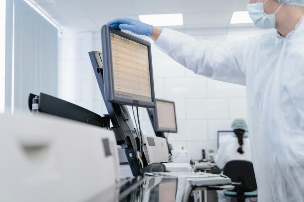 Scientist stands in front of a machine looking at the results of an experiment.